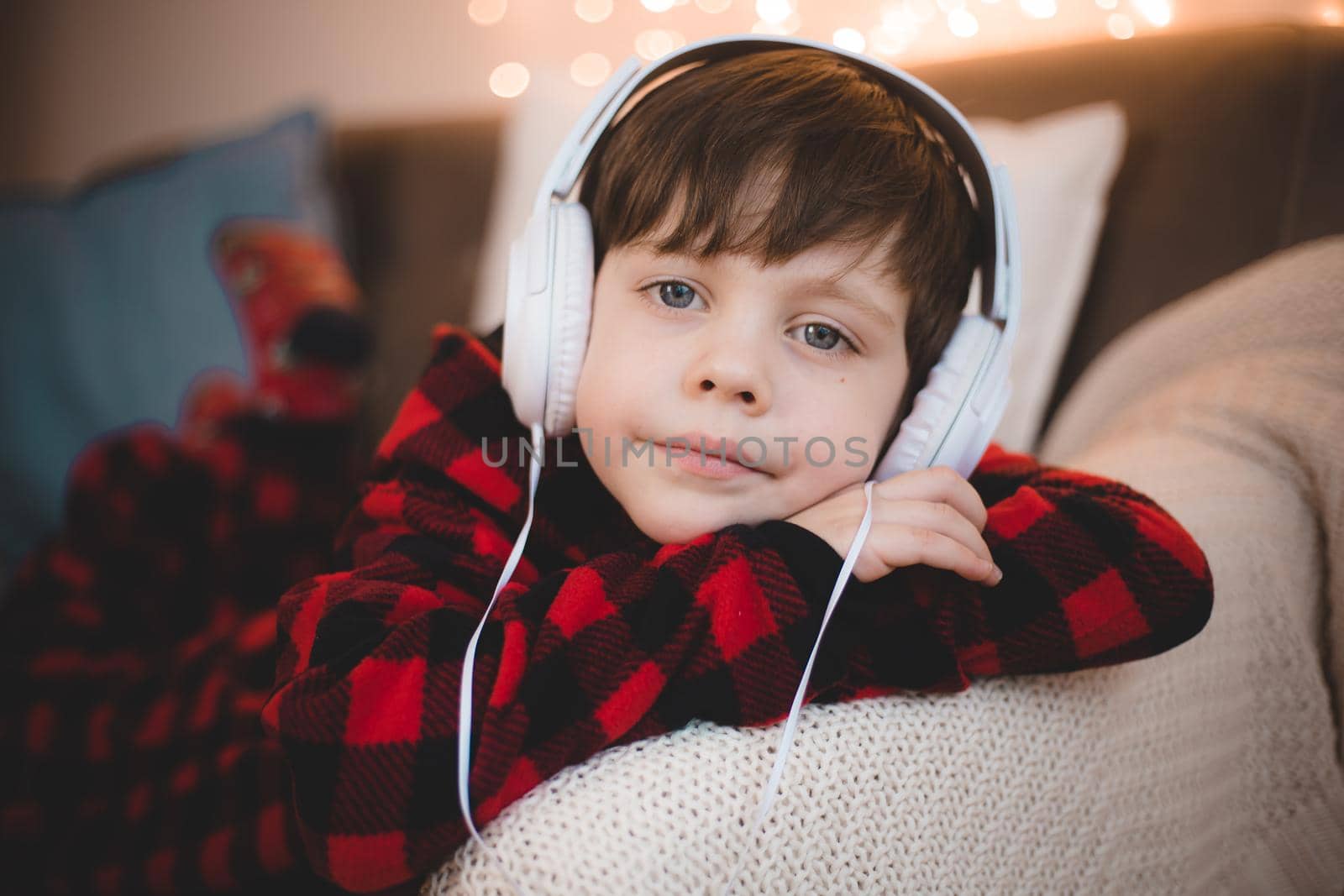 A boy with headphones is lying on the sofa lifestyle. The boy listens to music. by alenka2194