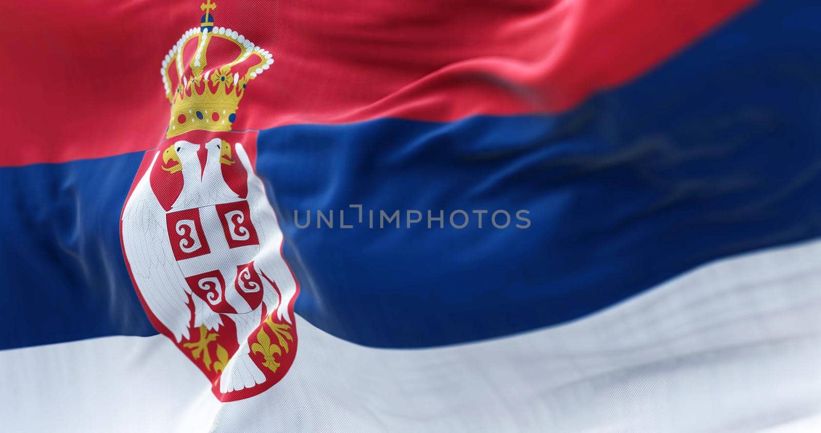 Close-up view of the Serbia national flag waving in the wind. Serbia is a landlocked country in Southeastern and Central Europe. Fabric textured background. Selective focus