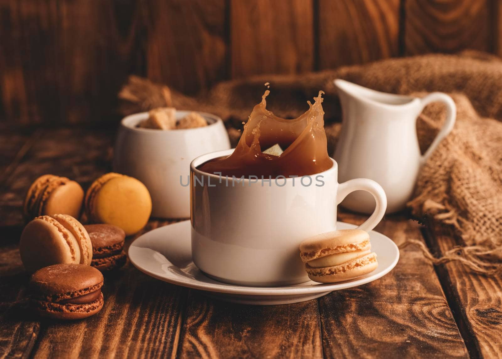 cup of black offee, milk, sugar and macaroons on wooden background