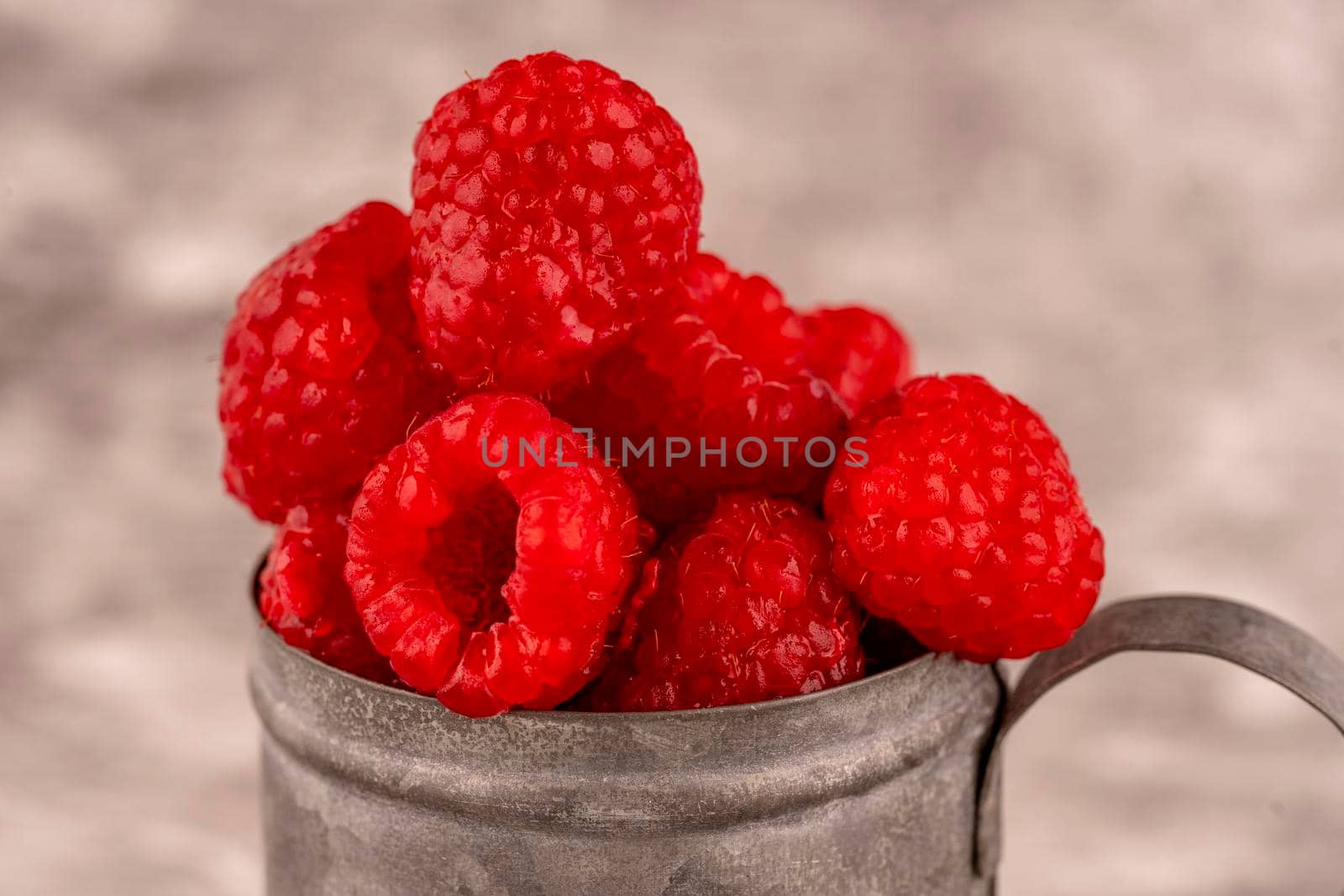 fresh raspberry berries in a cup on brown background by Iryna_Melnyk