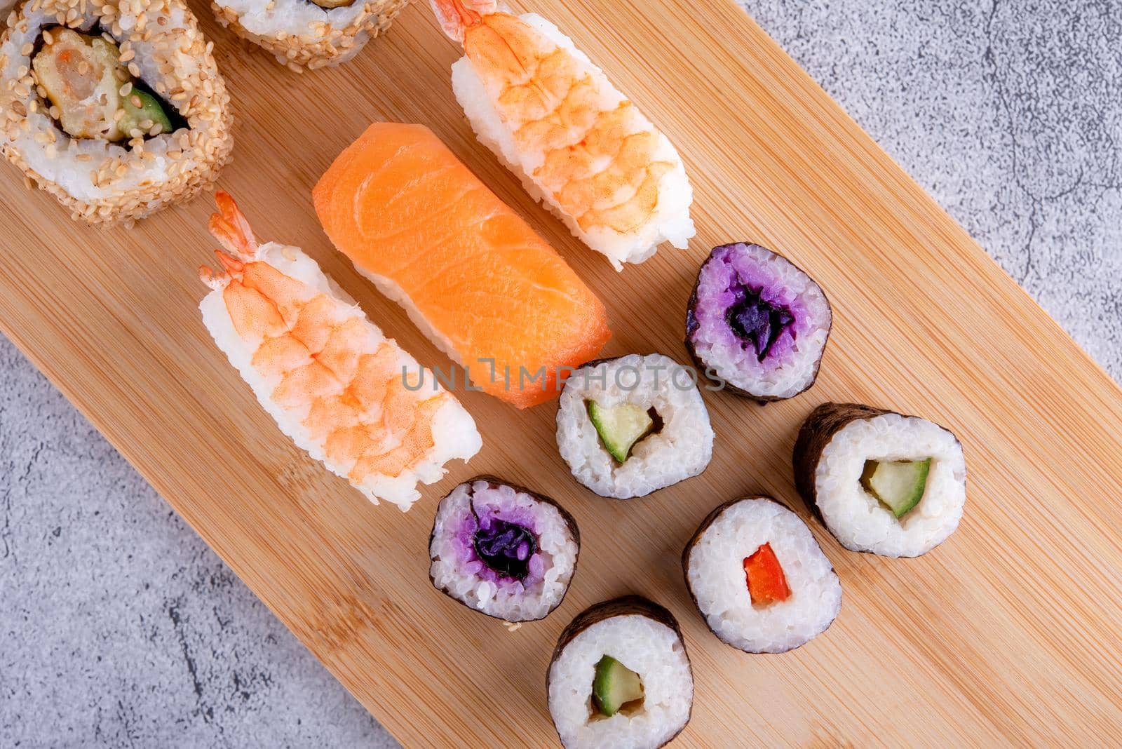 sushi set with chopsticks and soy on a wooden plate ready to eat on grey background