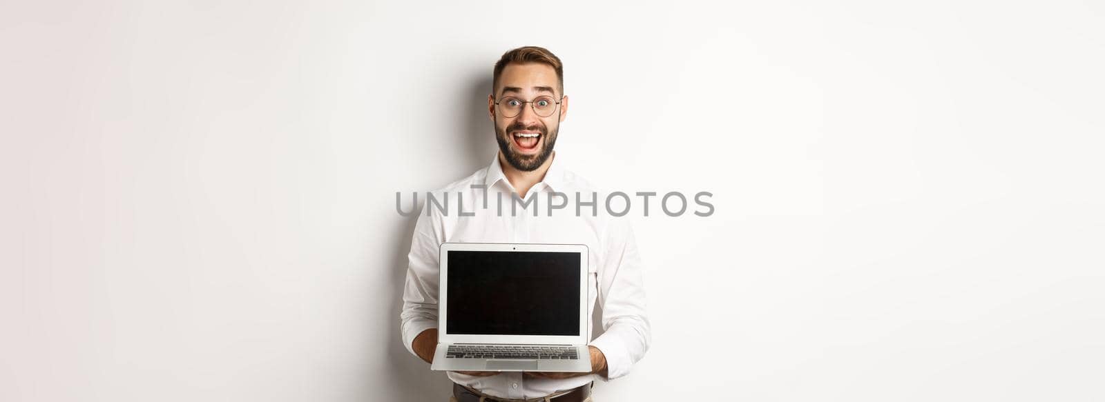 Excited businessman showing something on laptop screen, standing happy over white background by Benzoix