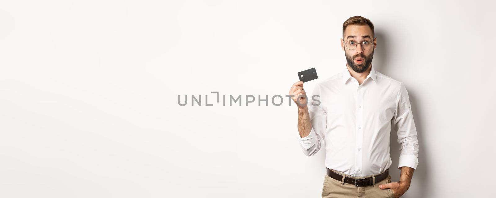 Man looking intrigued and showing credit card. Concept of shopping.