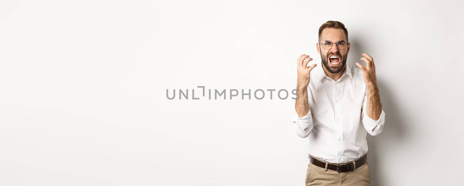 Frustrated and angry man screaming in rage, shaking hands furious, standing over white background by Benzoix