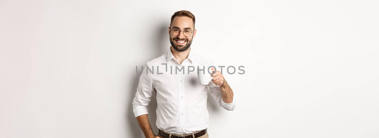 Handsome businessman drinking coffee and smiling, standing against white background by Benzoix