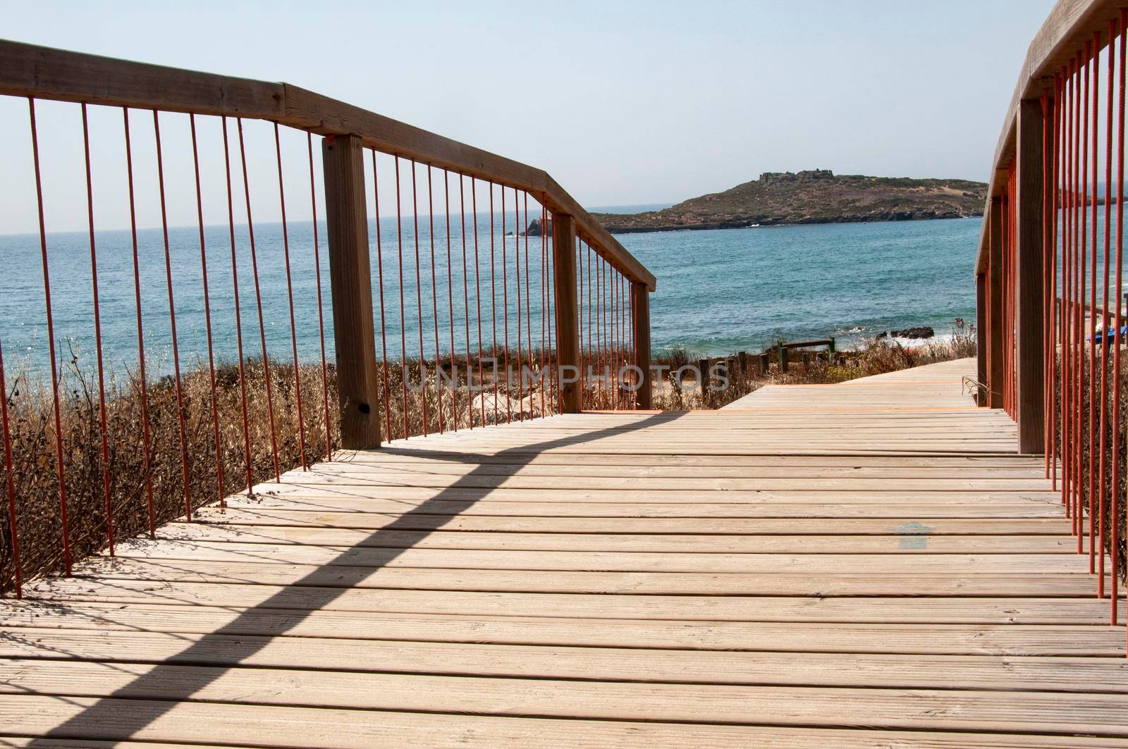 Wooden footpath on a beach entrance near Porto Covo, Portugal. Peach tree island in the background. by papatonic