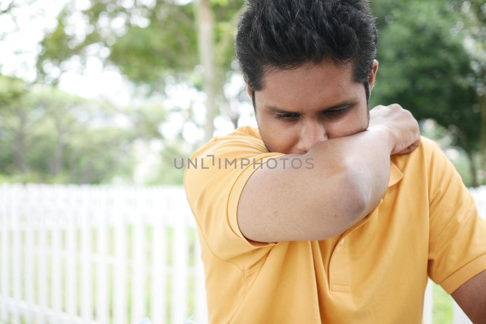 Young ill man covering her nose and mouth with arm