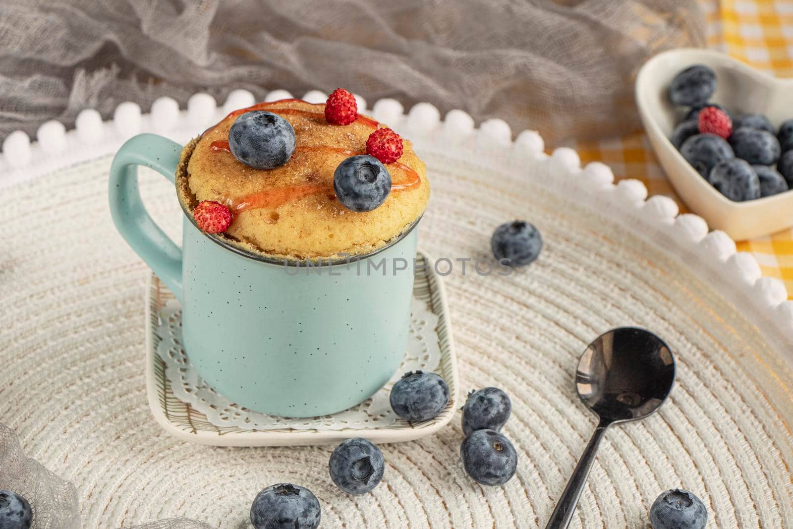 Delicious homemade blueberry muffin mug cake with fresh berries . Cooked in a cup in the microwave. cupcake in a blue mug decorated with blueberries. vanilla mugcake dessert. Easy to cook concept