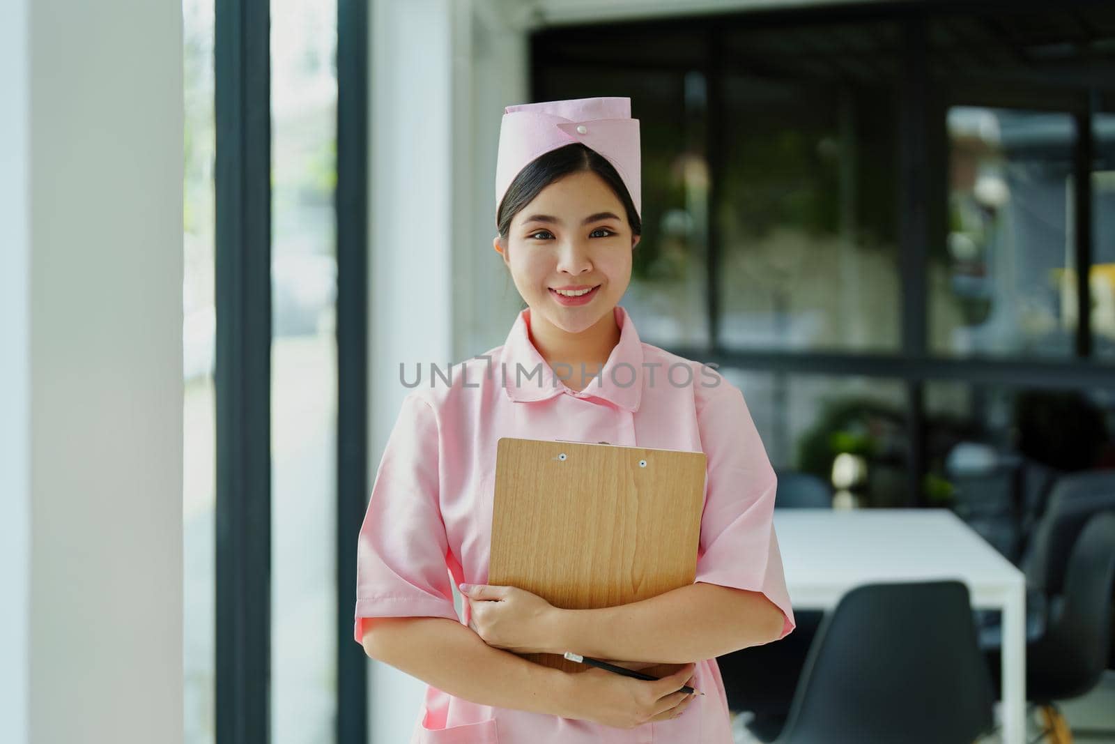 Portrait of a young nurse in a pink dress smiling happily.