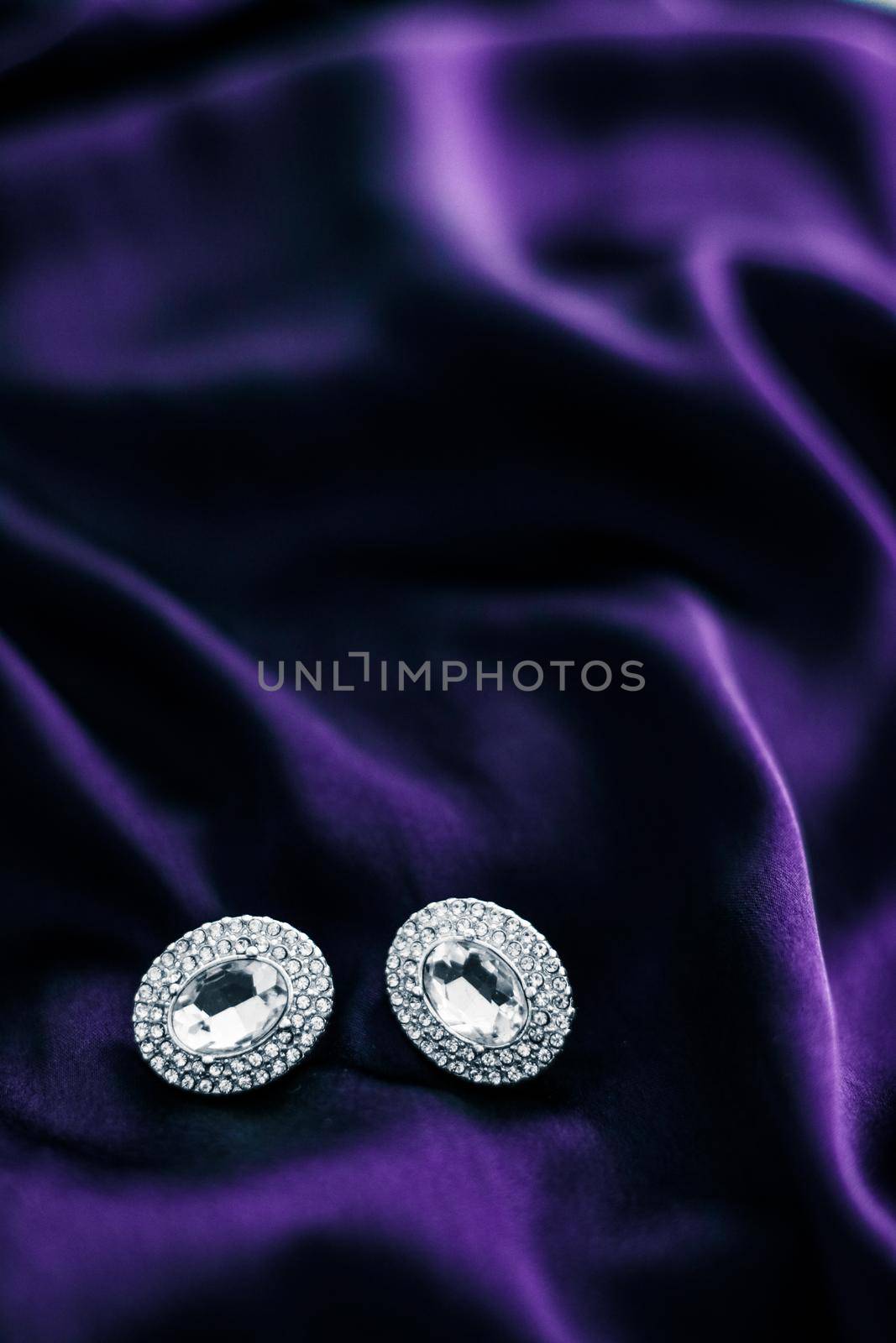 Luxury diamond earrings on dark violet silk fabric, holiday glamour jewelery present by Anneleven