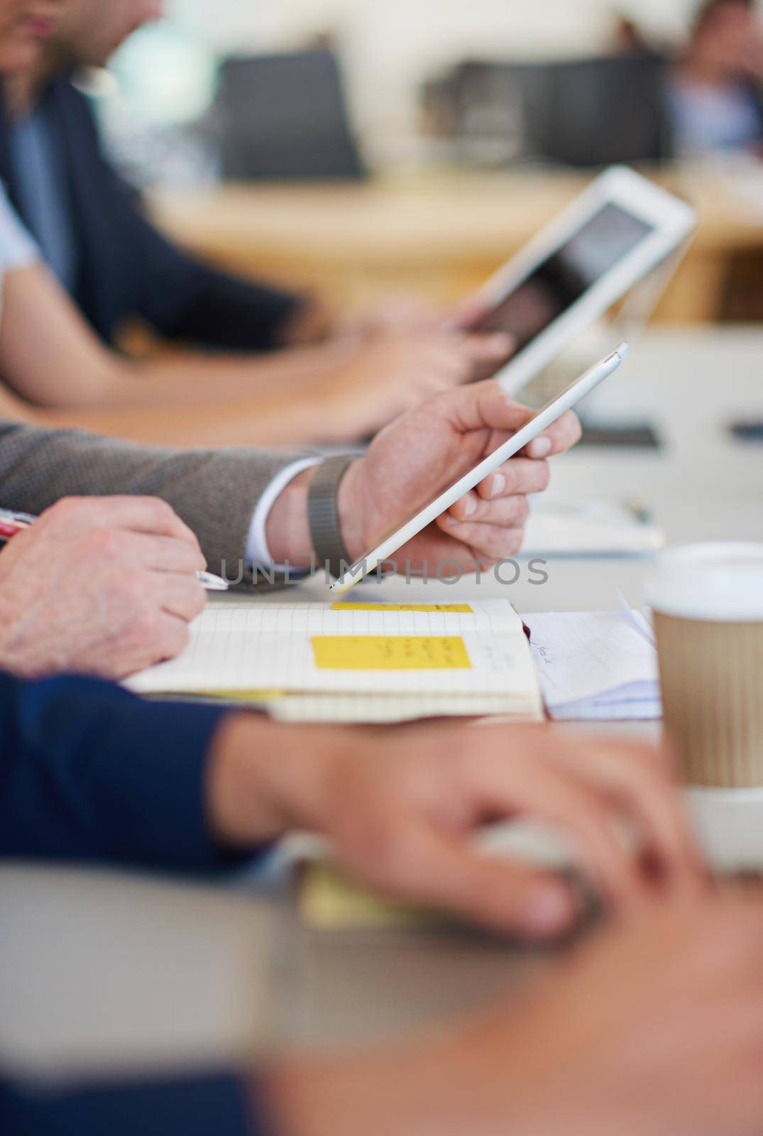 Let technology do the thinking. a group of business professionals sitting around the table in a meeting while using modern technology. by YuriArcurs