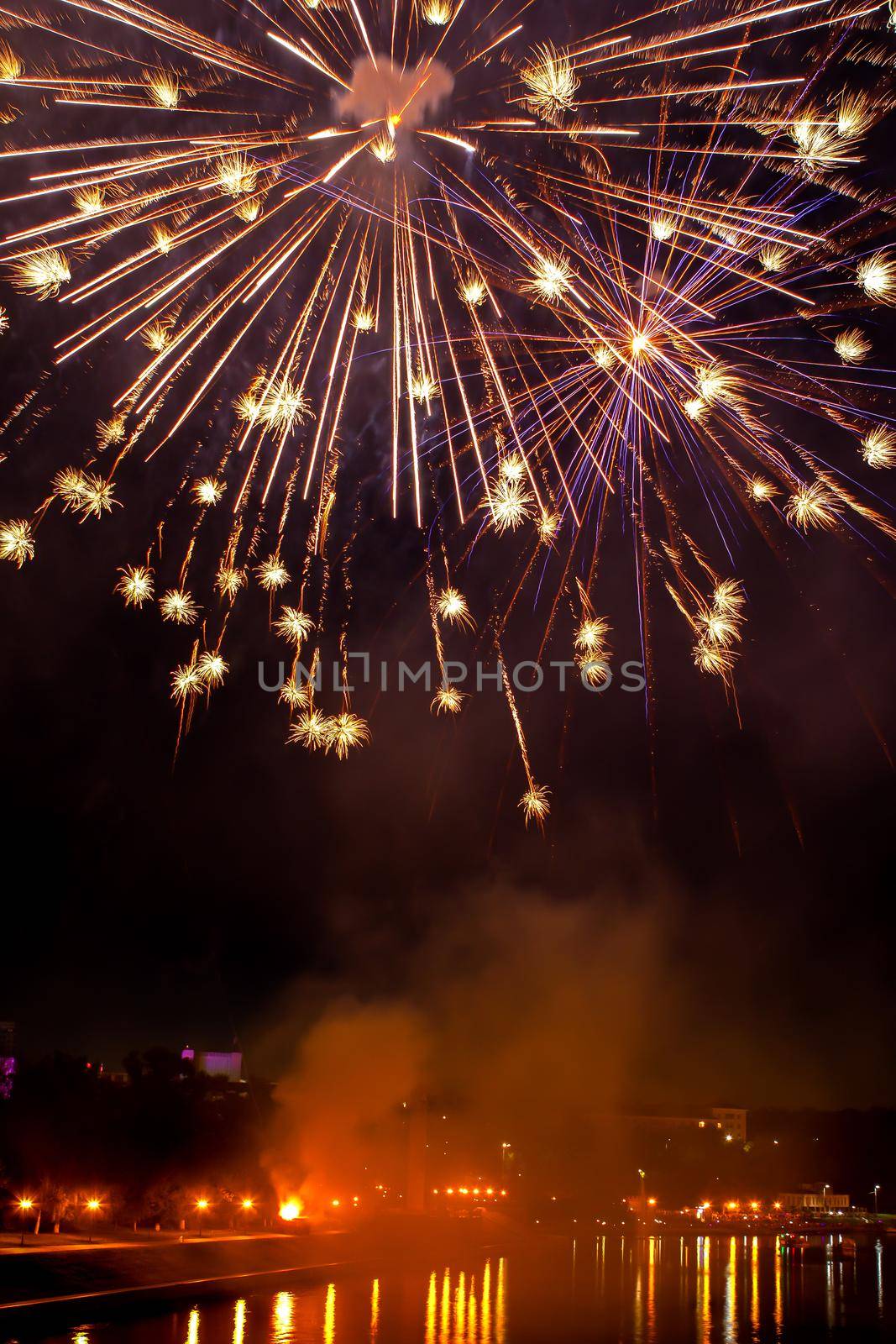 Fireworks in evening sky over river in city. Holiday concept. Vertical position of frame by Laguna781