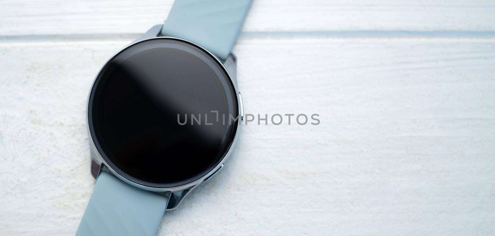 Smart watch with digital screen and copy space lying on white table background. Innovative gadget with touchscreen in luxury design