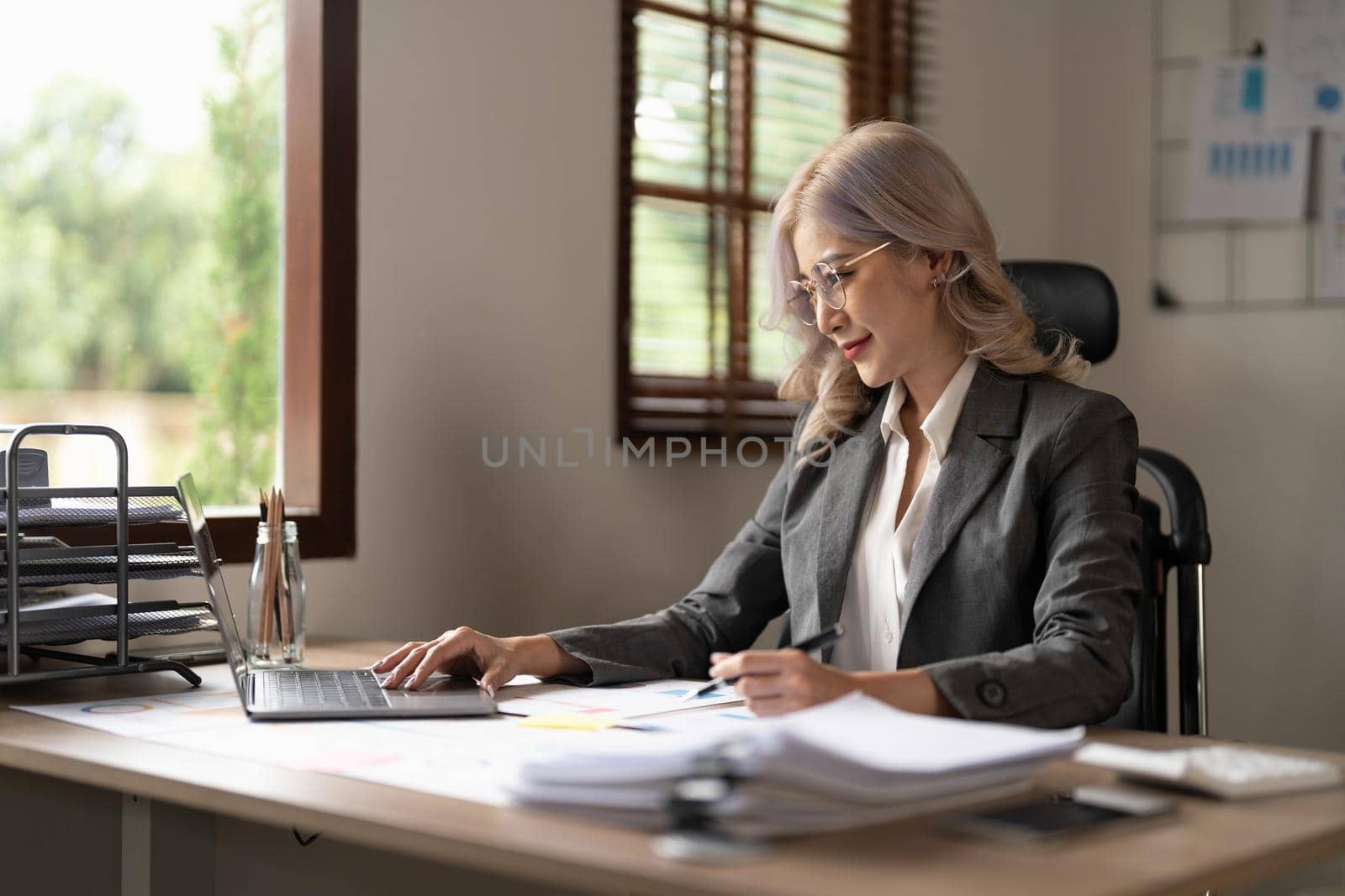 Charming businesswoman working on laptop at her workplace at modern office