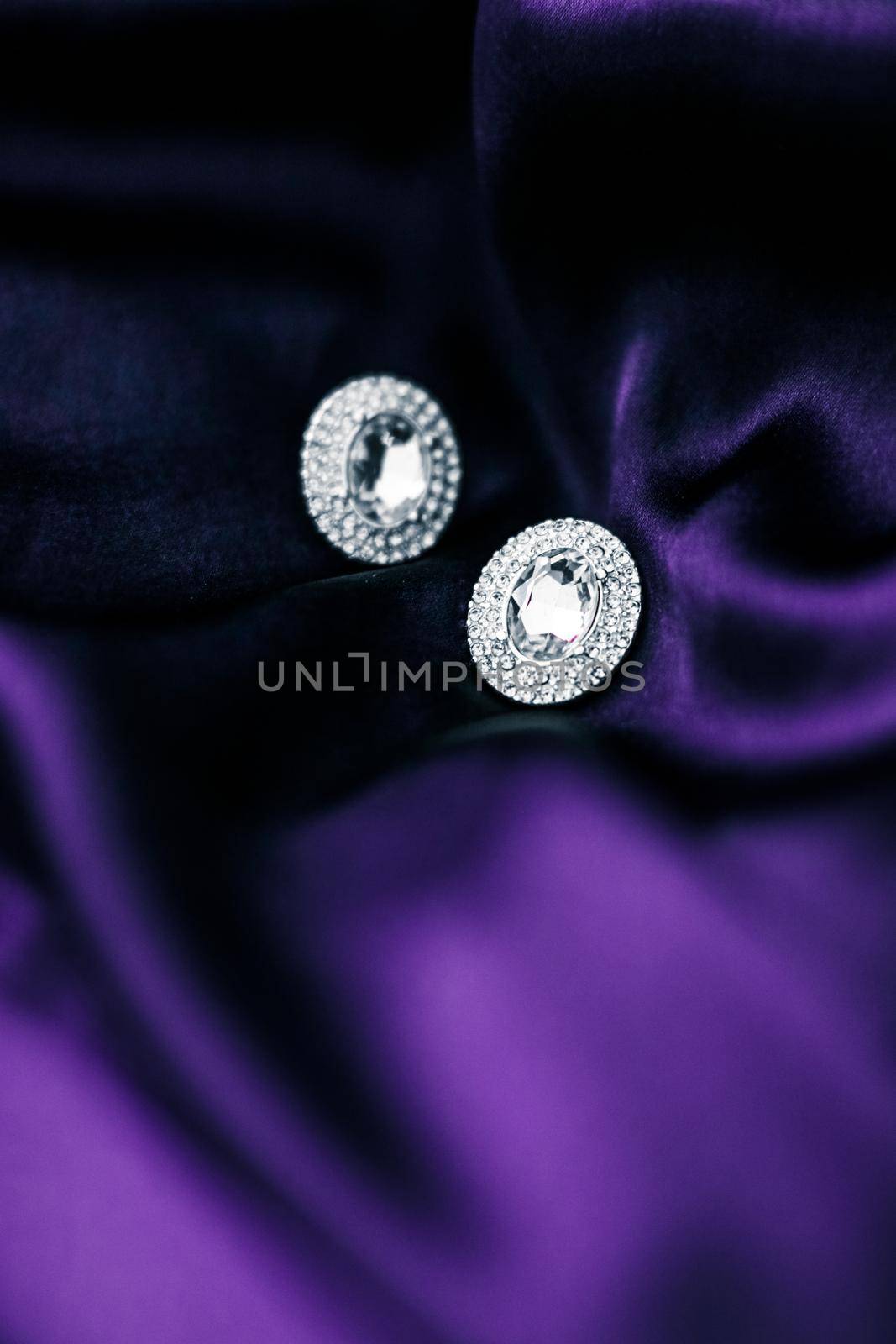 Luxury diamond earrings on dark violet silk fabric, holiday glamour jewelery present by Anneleven