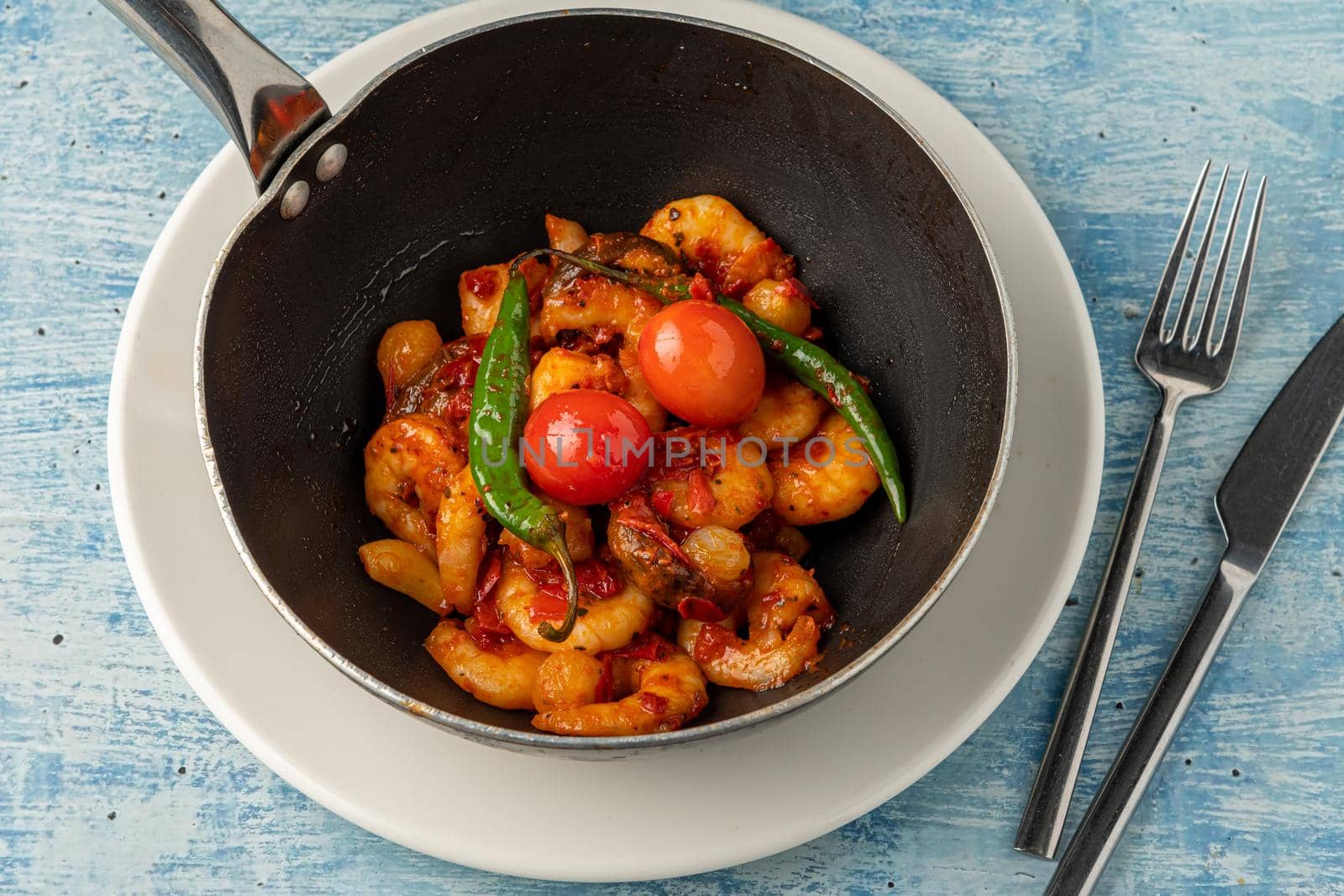 Shrimp casserole with tomatoes, garlic and peppers in black wok pan by Sonat