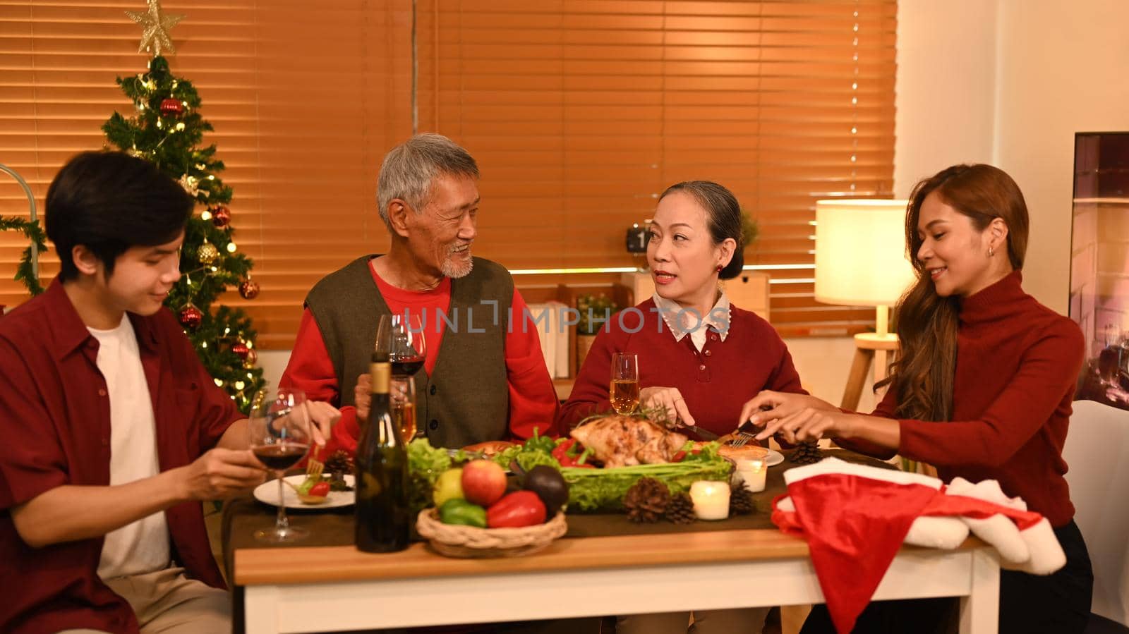 Young couple with grandparents enjoying Thanksgiving meal in comfortable home. Celebration, holidays and Christmas concept by prathanchorruangsak