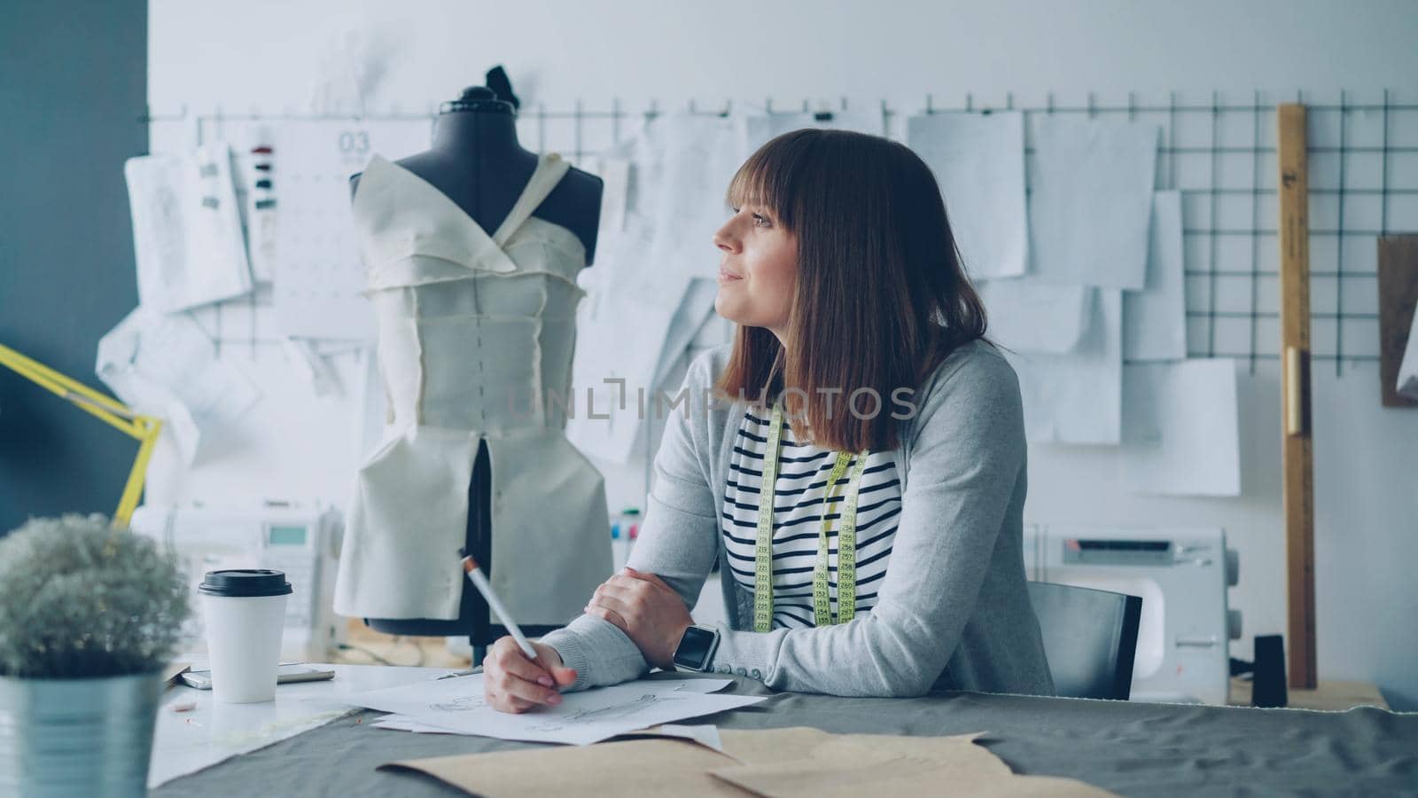 Clothing designer in small start-up business is drawing sketches for women's clothes and thinking about next fashion show. Inspiration and creative thinking concept. by silverkblack