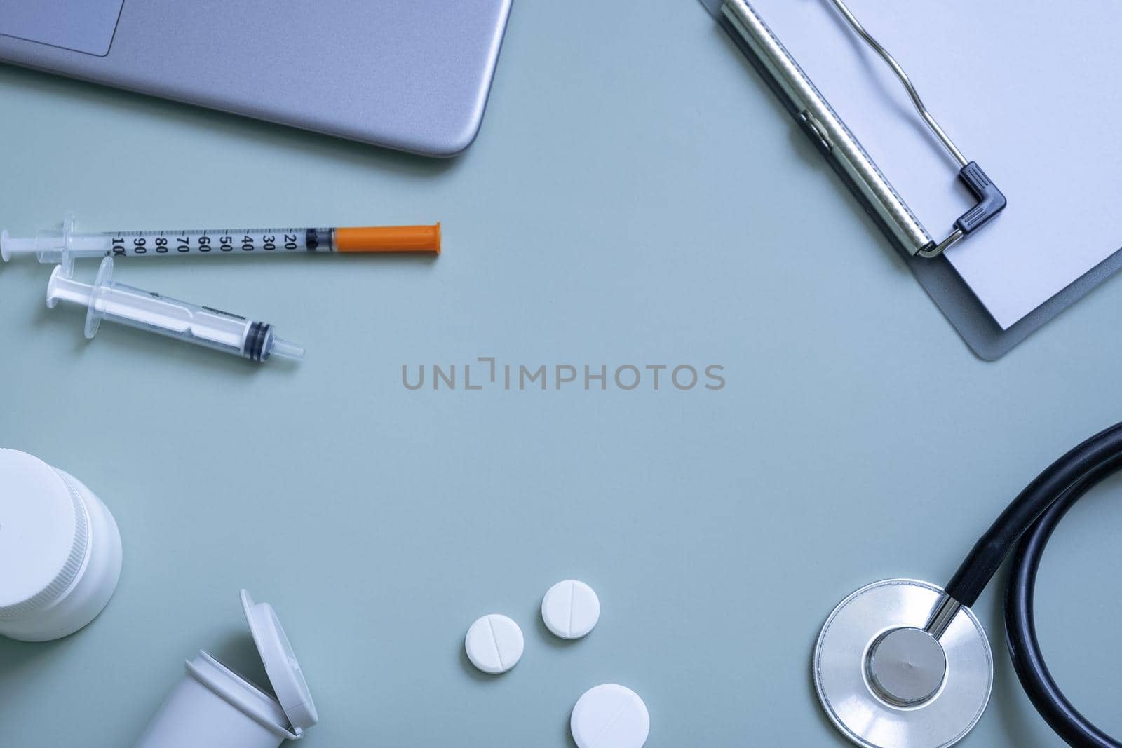 Stethoscope, syringes, pills and tablet at doctor's workplace on colored background top view. Medical flat lat with copy space.