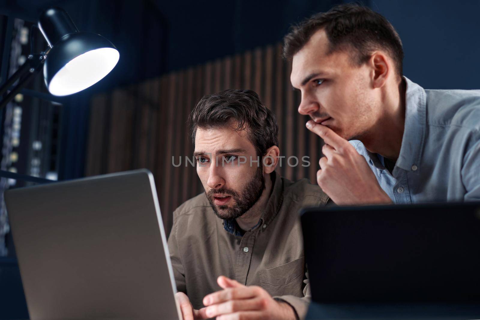 business colleagues standing in front of an open laptop in a night office. close-up.