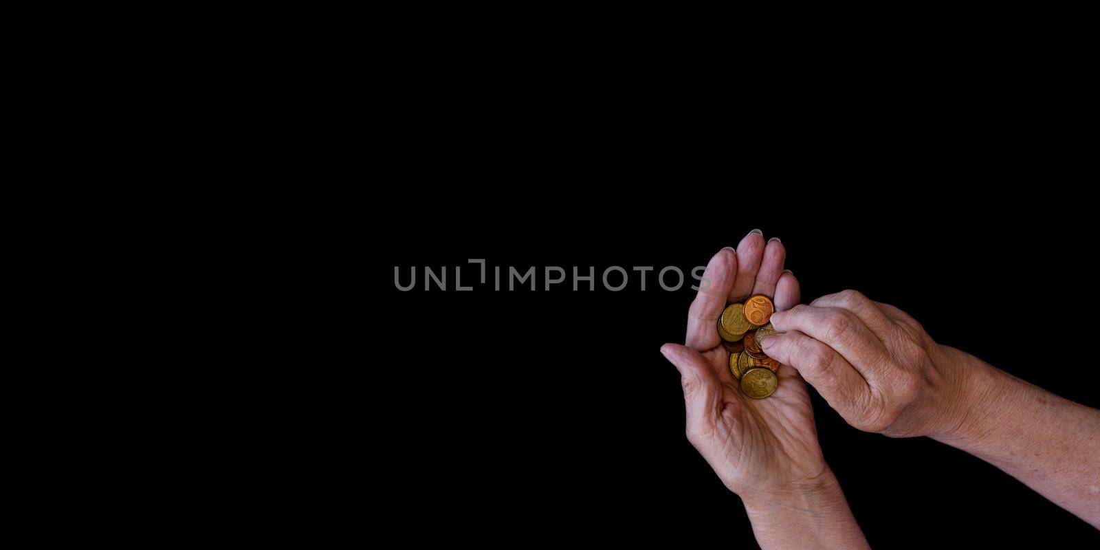 Big banner, black background with copy paste. The hands of an elderly woman with arthritis count coins in her hands. The concept of poverty, benefits for the elderly, old age