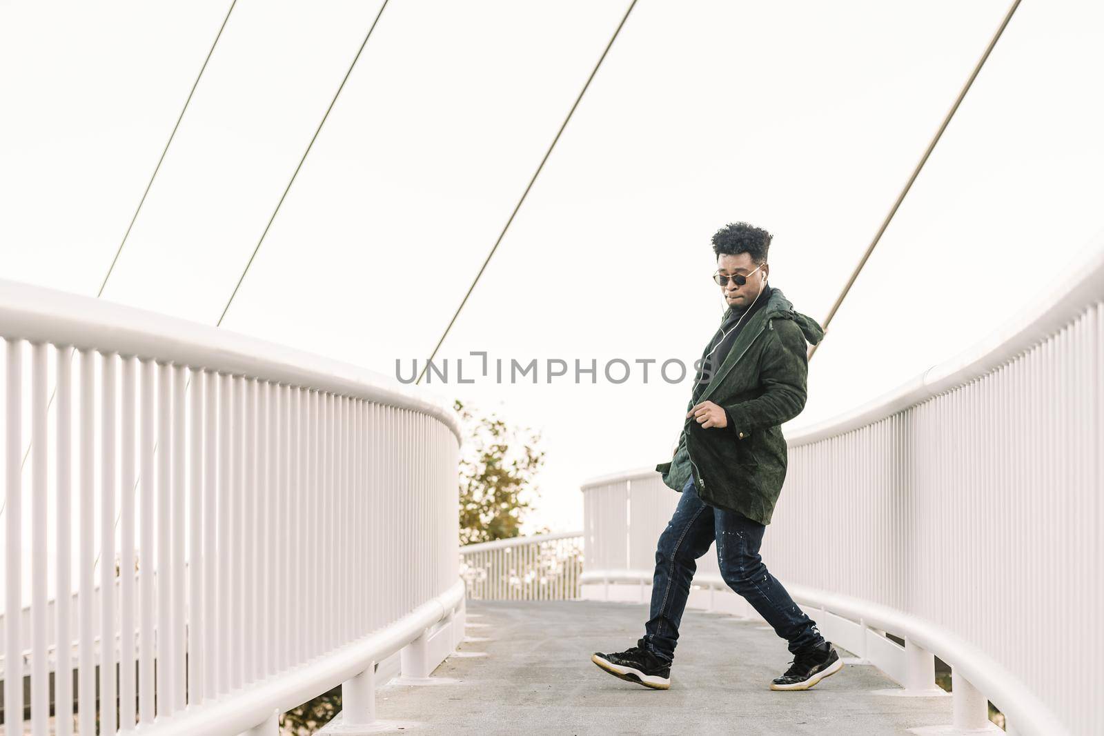 happy black man with earphones dancing at city by raulmelldo