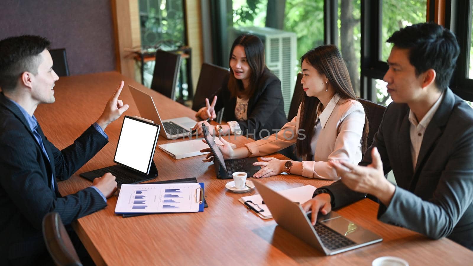 Group of successful business people discussing financial report of their company in boardroom.