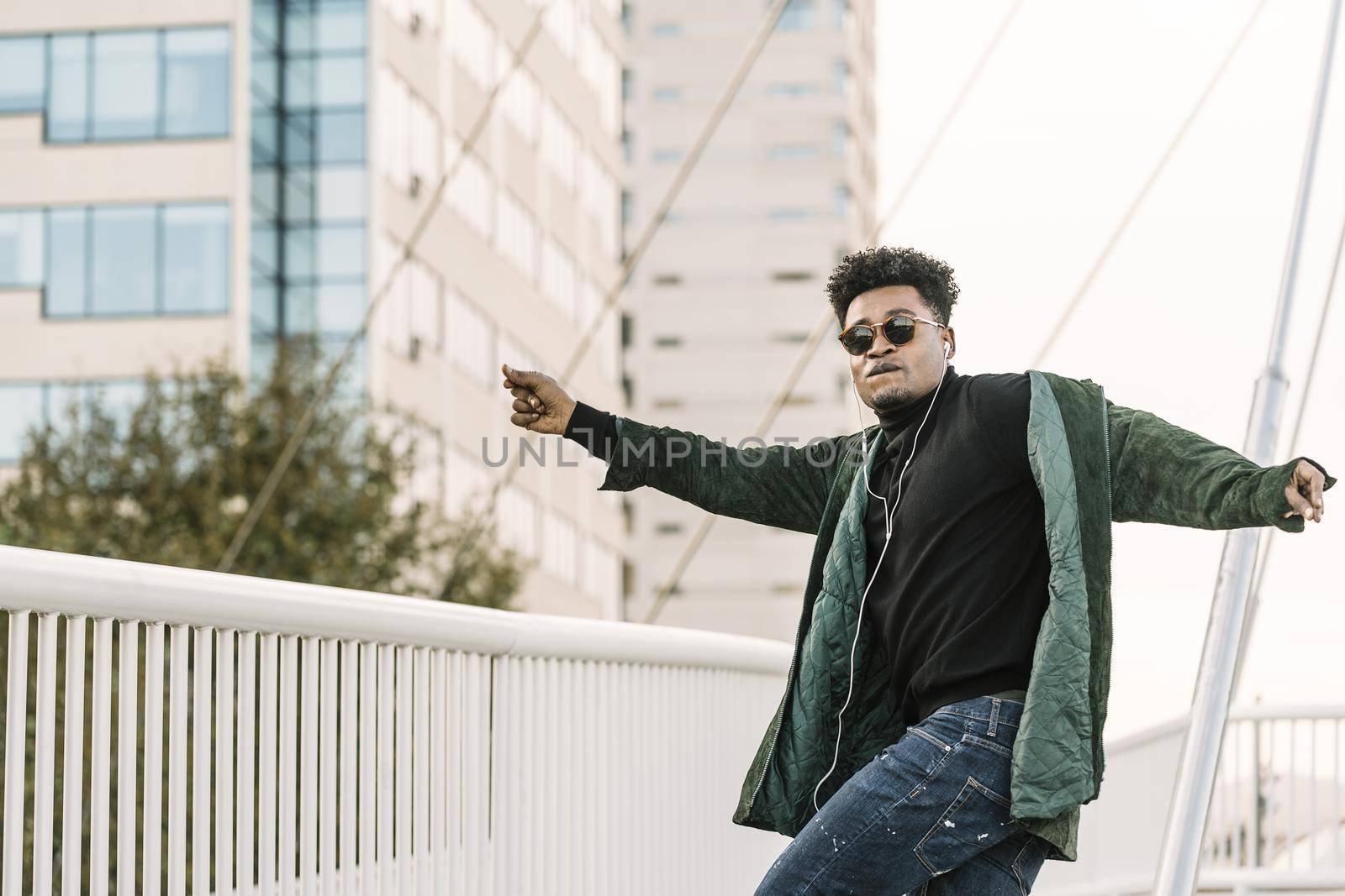 black man dancing happy in the city with earphones by raulmelldo