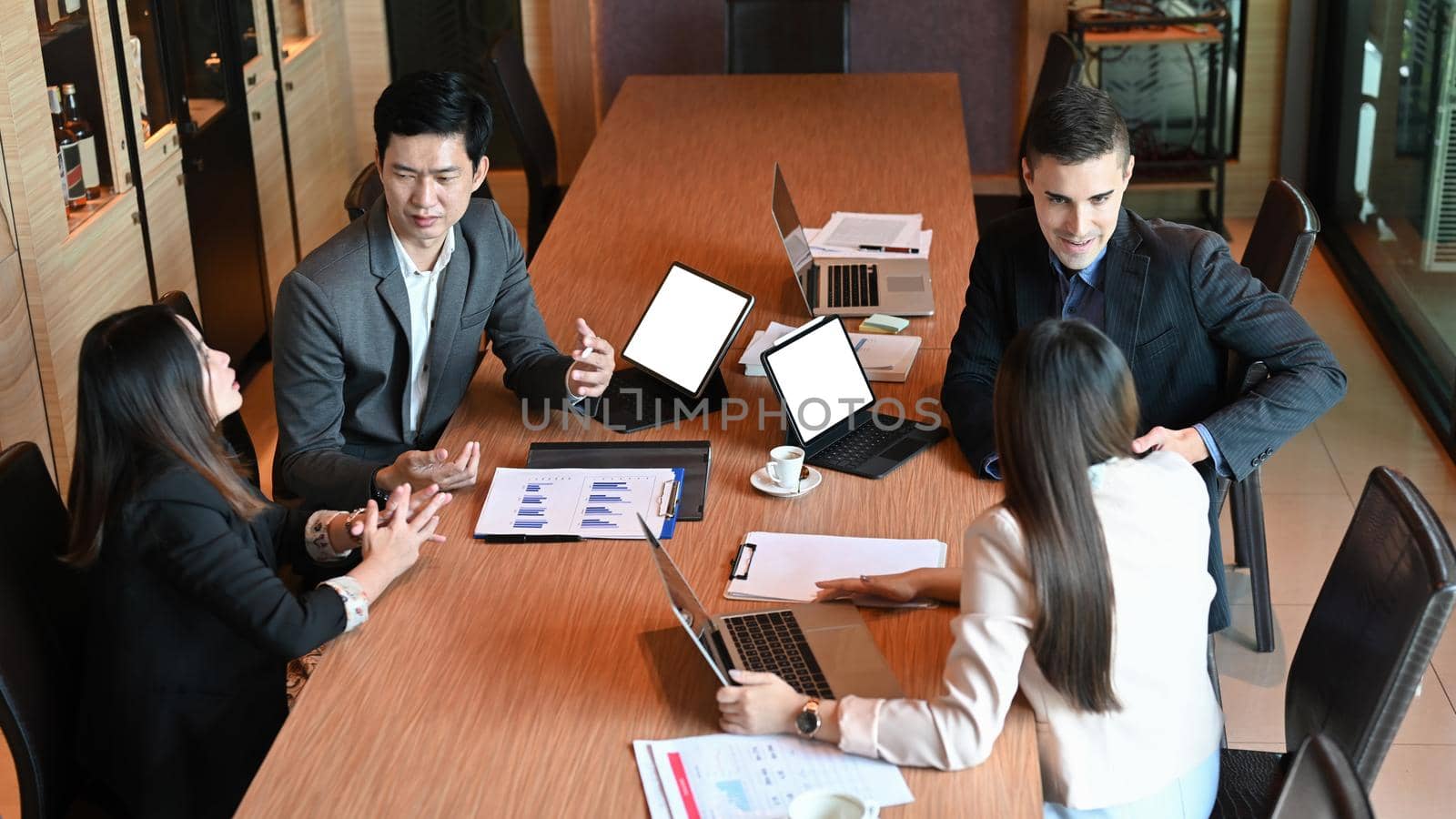 Diverse business people brainstorming and discussing financial report together in boardroom.