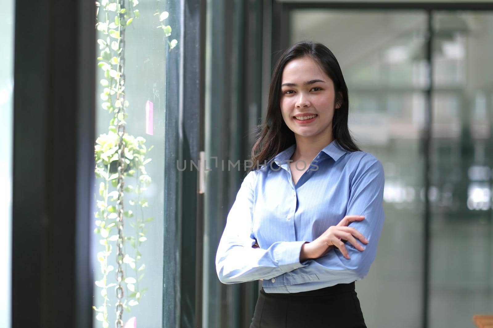 Young confident smiling Asian business woman leader, successful entrepreneur, elegant professional company executive ceo manager. Asian business woman is standing in office with arms crossed