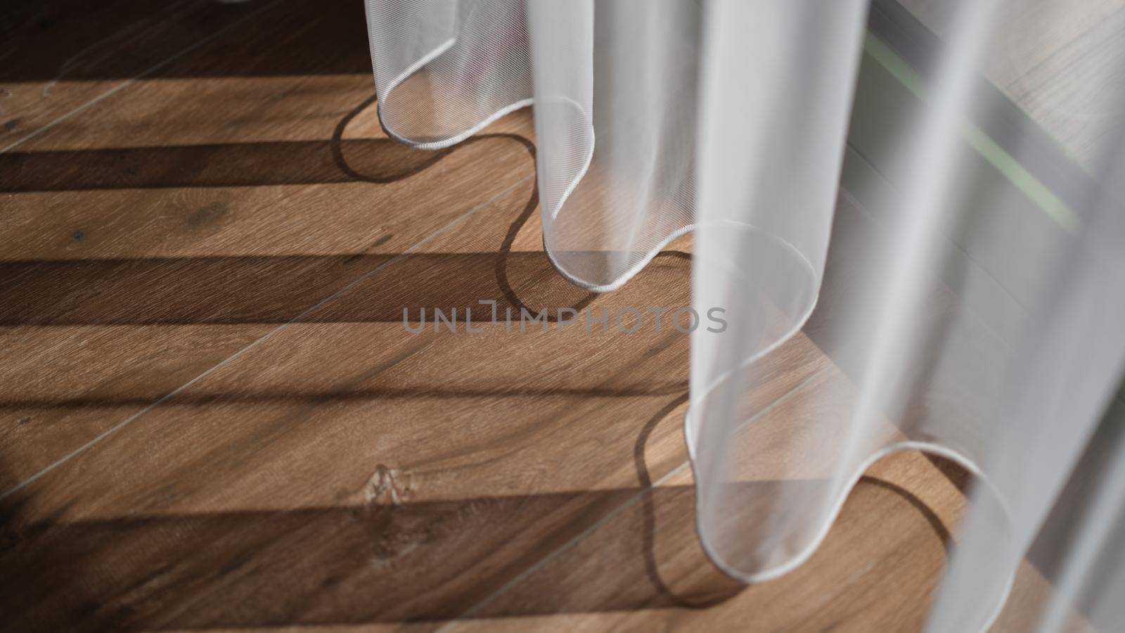 Shadow from white curtains on wooden floor background. Quality laminate flooring concept