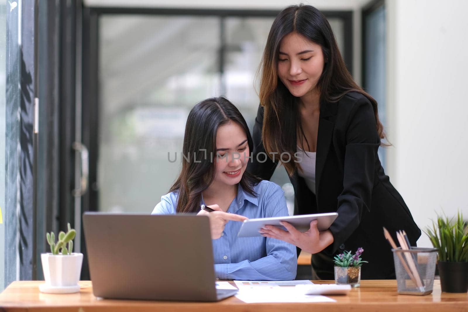 Two Young Asian businesswoman discuss with new startup project Idea presentation, analyze planning and financial statistics and investment market at office. by wichayada