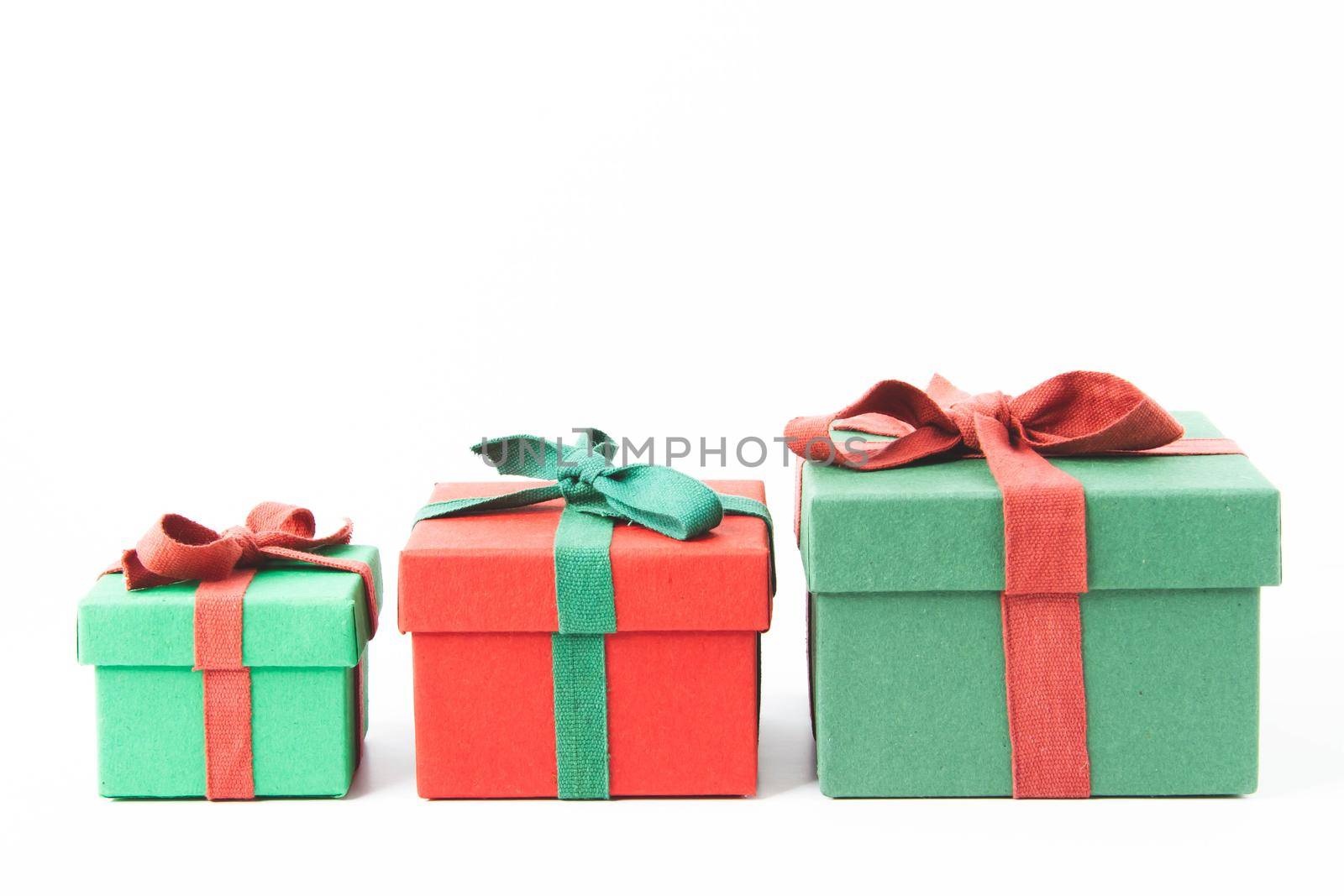 Present. Gift box with a bow. New Year's surprise. Red and green box with a gift. On a white background, top view. Close-up. Tied with a beautiful ribbon for gifting. Under the tree.