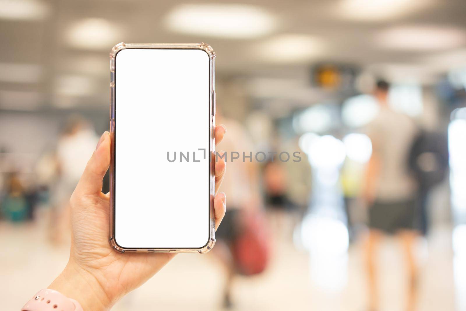 Hand holding smartphone with blank screen white Isolated on blur airport background. by sirawit99