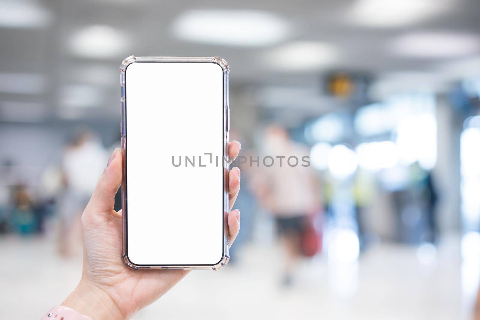 Hand holding smartphone with blank screen white Isolated on blur airport background. by sirawit99