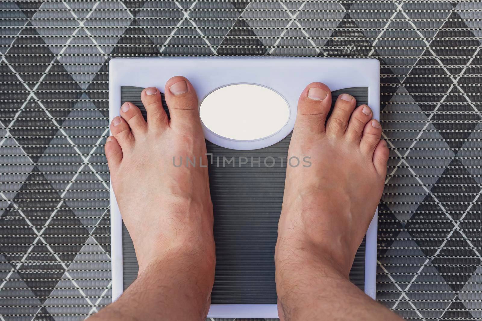 A man measures his weight on floor scales while standing barefoot