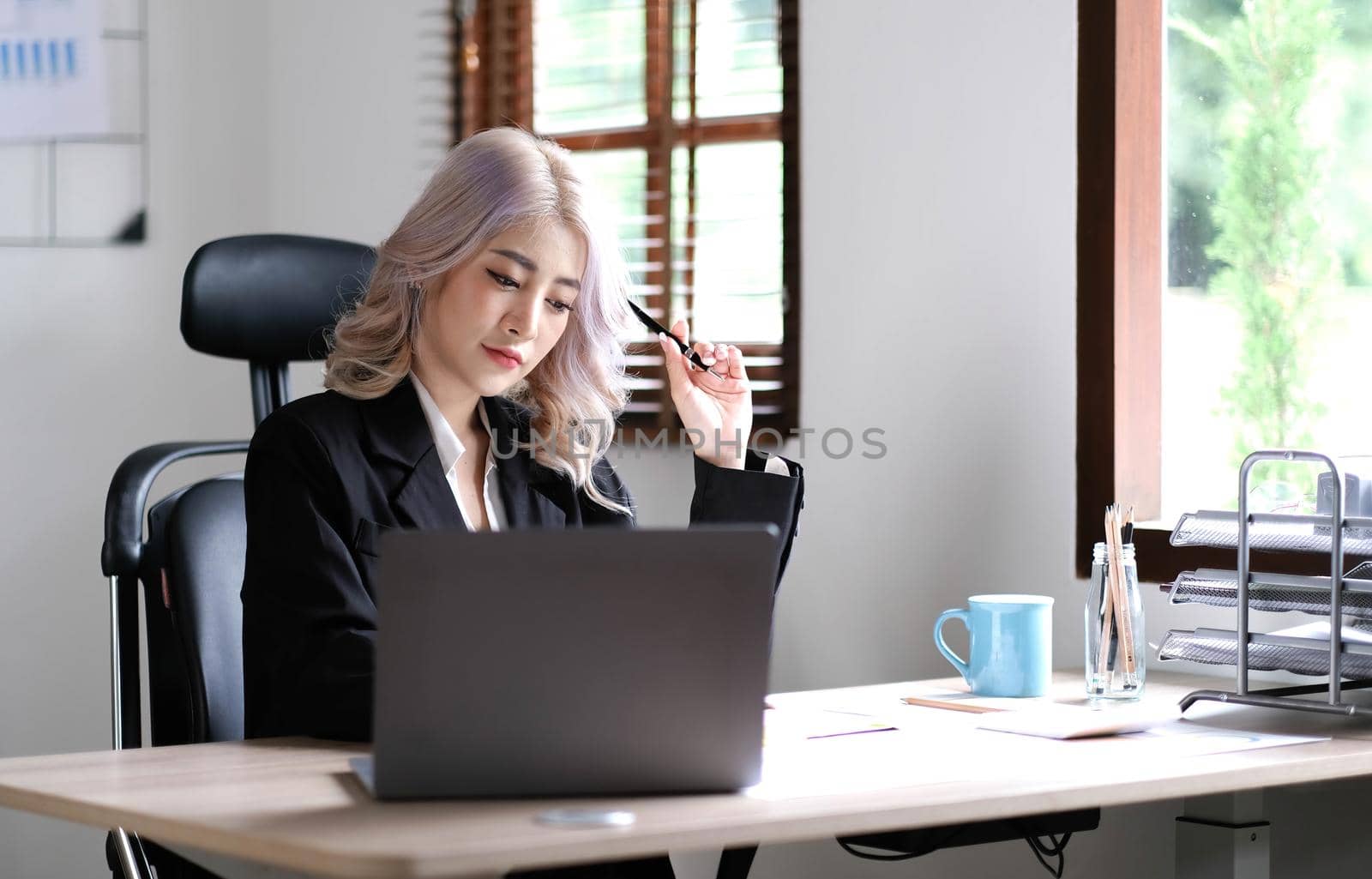 Young asian businesswoman have the pleasure of watching work on their tablet and favorite coffee at the office..