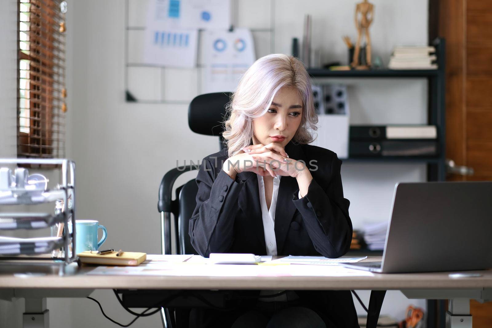 Image of an Asian business woman is stressed, bored, and overthinking from working on a tablet at the office..