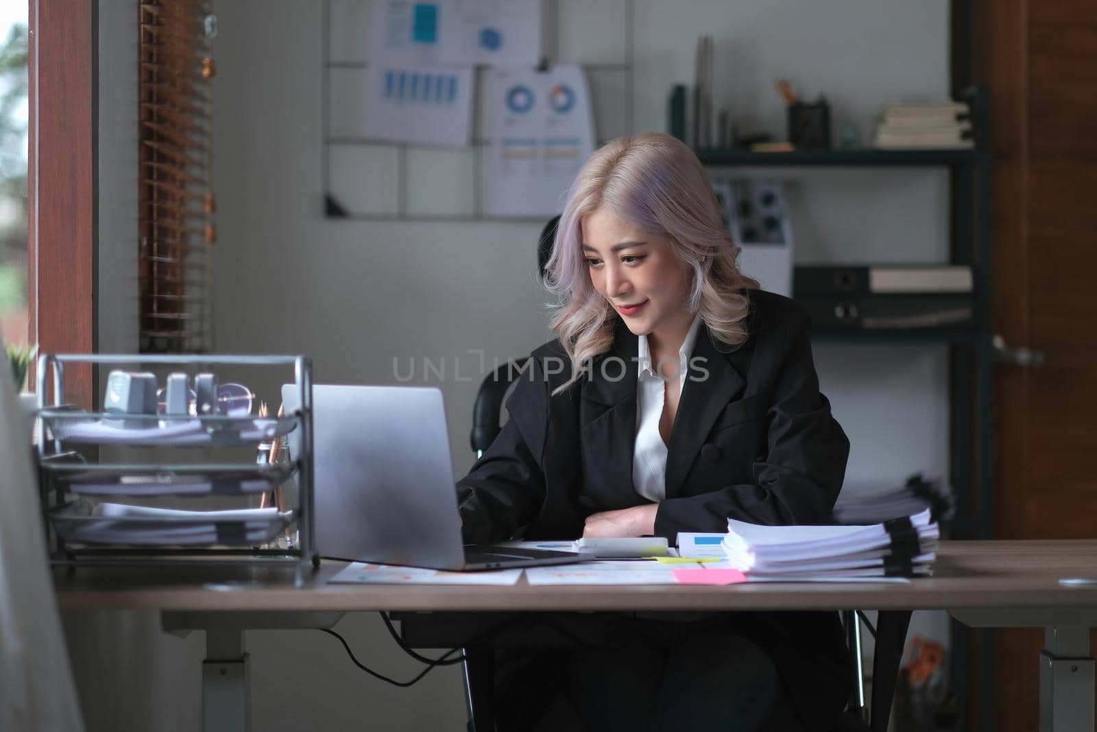 Smiling asian business woman sitting in a modern office..