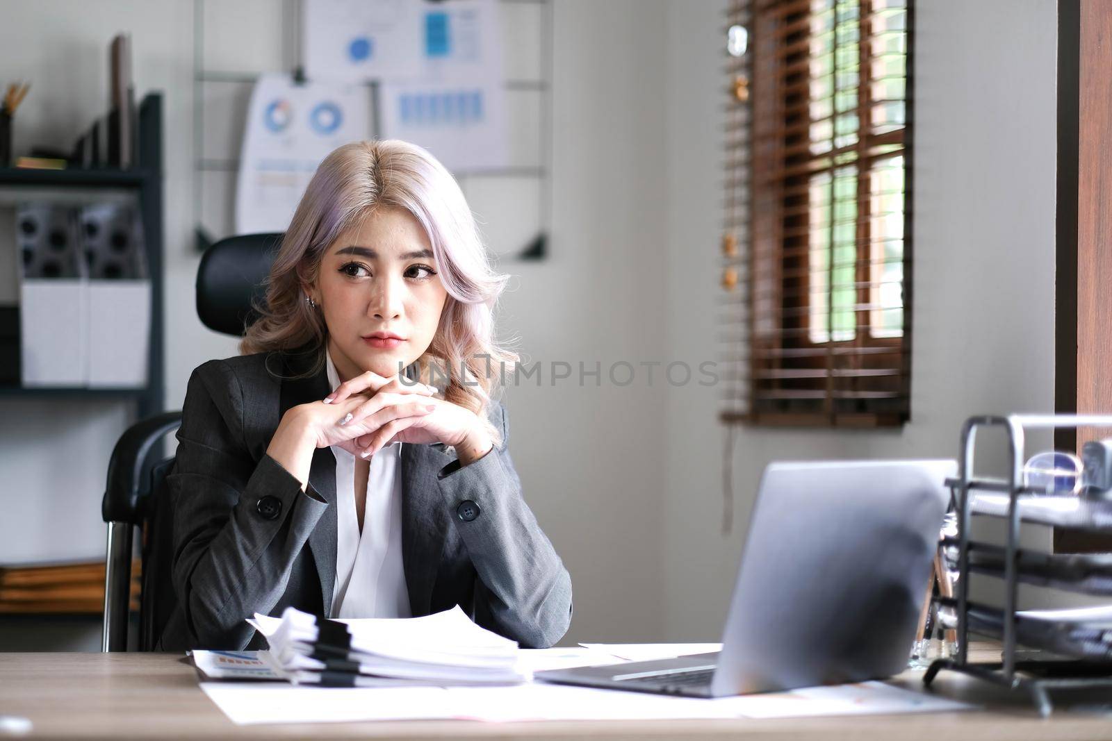 Image of an Asian woman who is tired and overthinking from working with a tablet at the office..