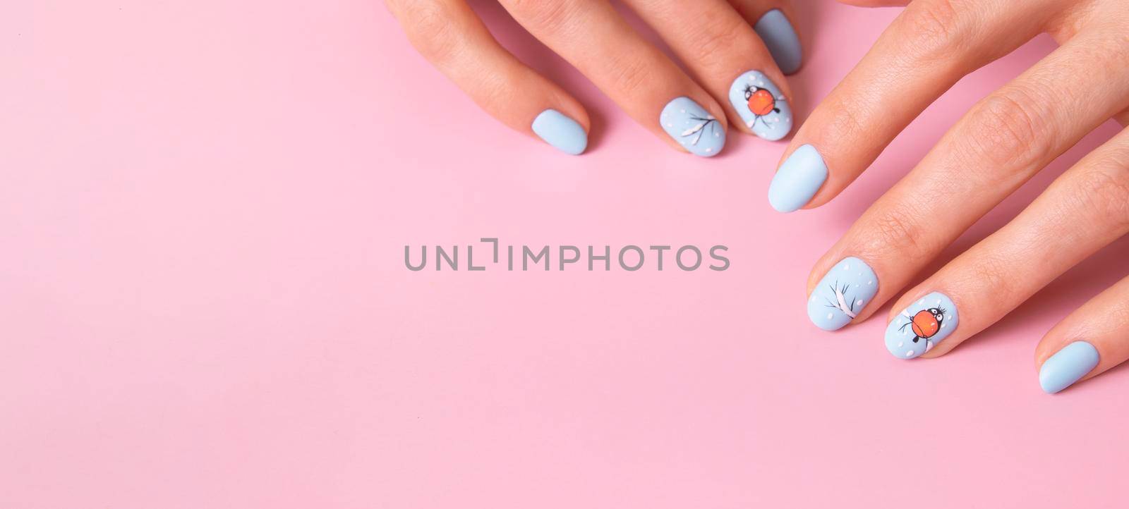 Banner with female hands with winter snow manicure with stickers under a matte top on pink background.