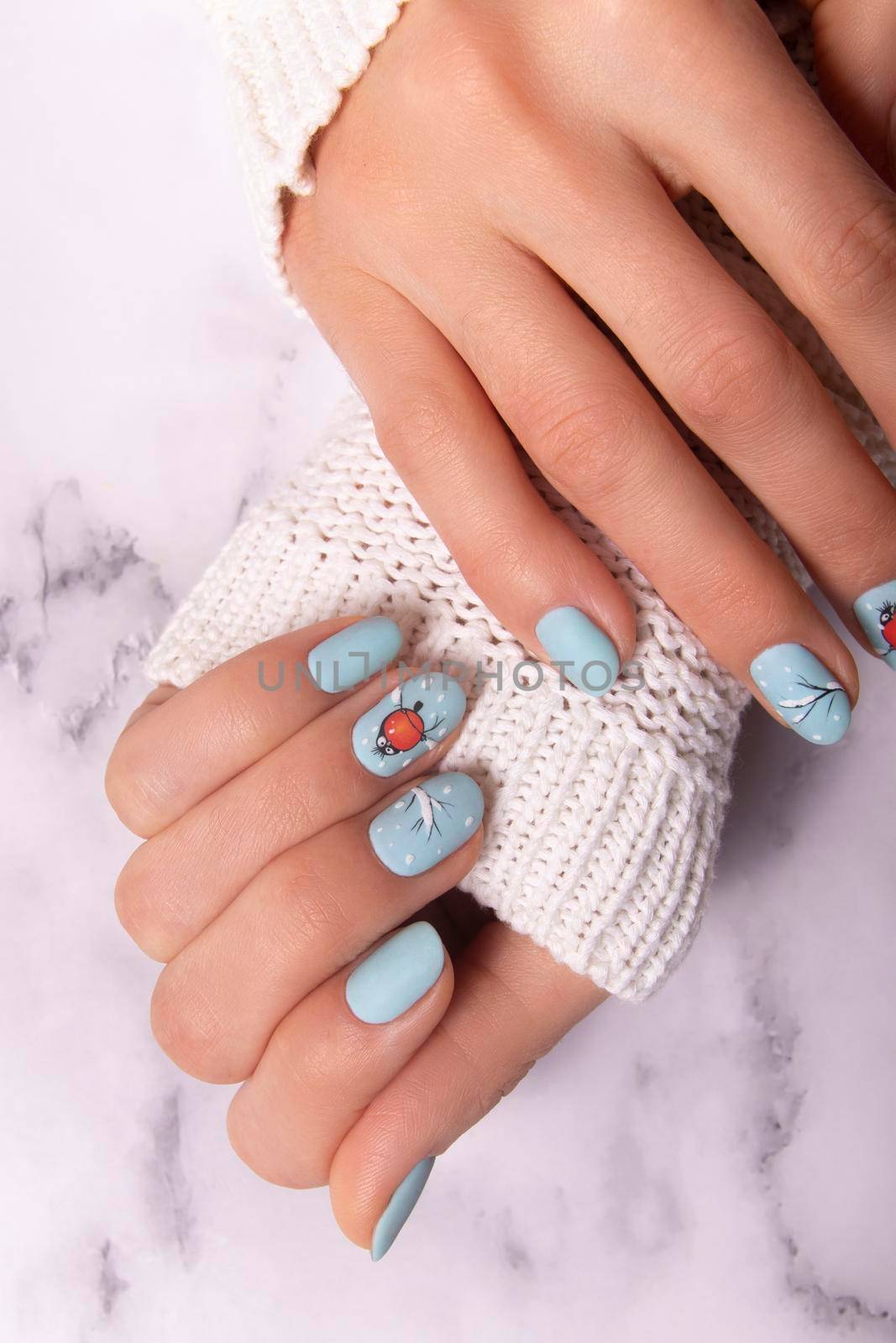 Female hands with winter snow manicure with stickers. Professional gel nail polish.