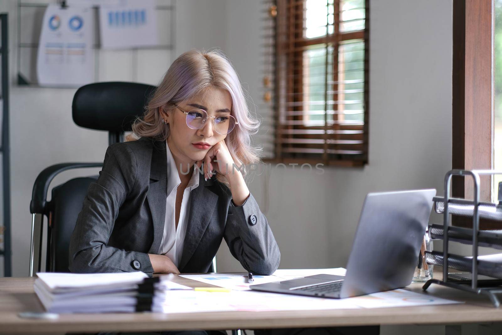 Tired business asian woman holds her fingers on her temples at work table. Irregular working day stressed worried, tired and overwhelmed concept.