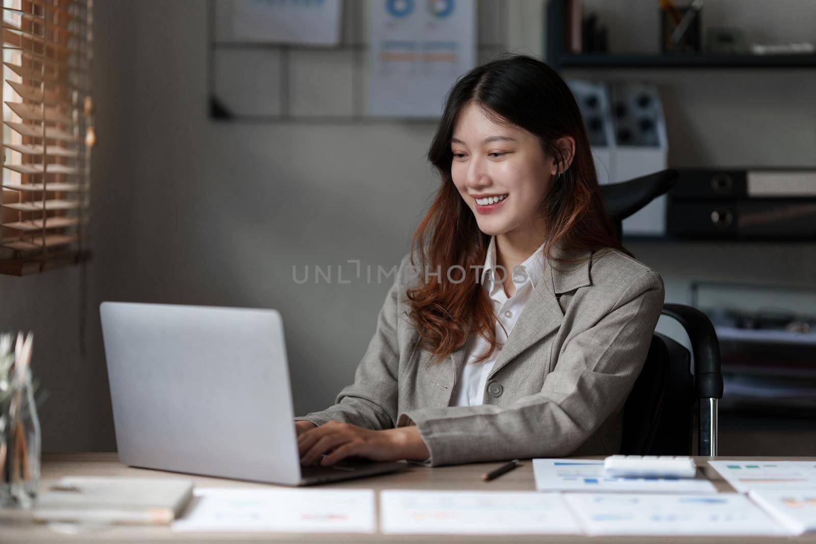 Asian Business Woman or Accountant do math and analyze with calculator and paperwork on desk, account, audit and saving concept.