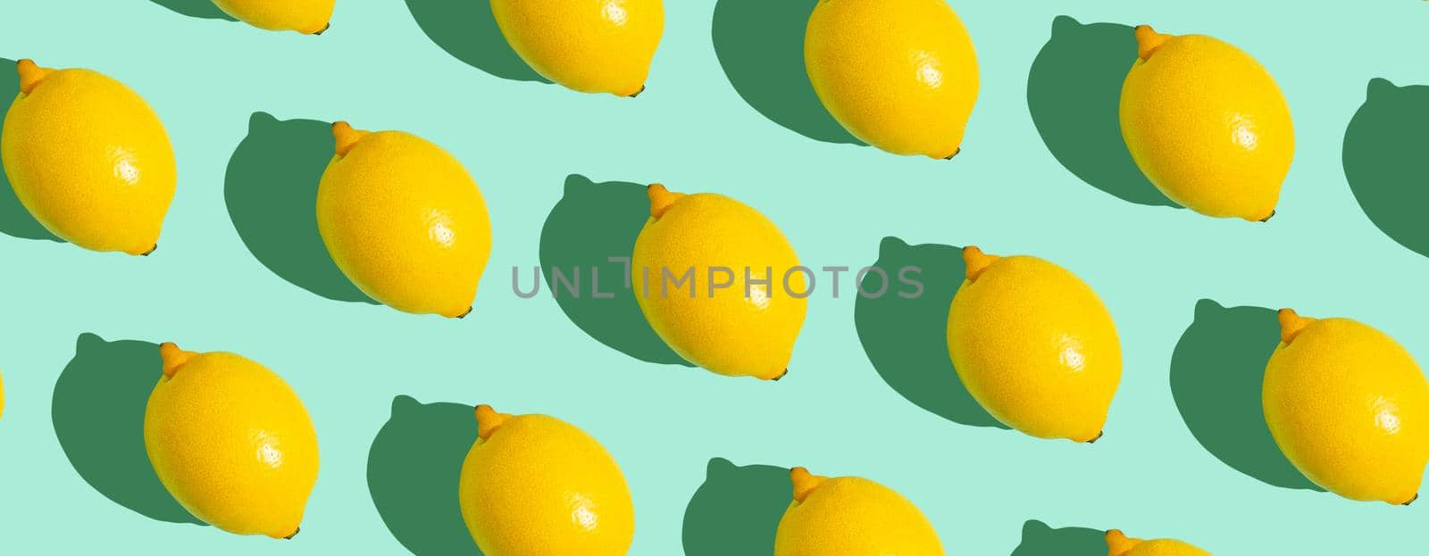 Yellow whole lemons on minimal blue background on bright sun light with hard shadows pattern by its_al_dente