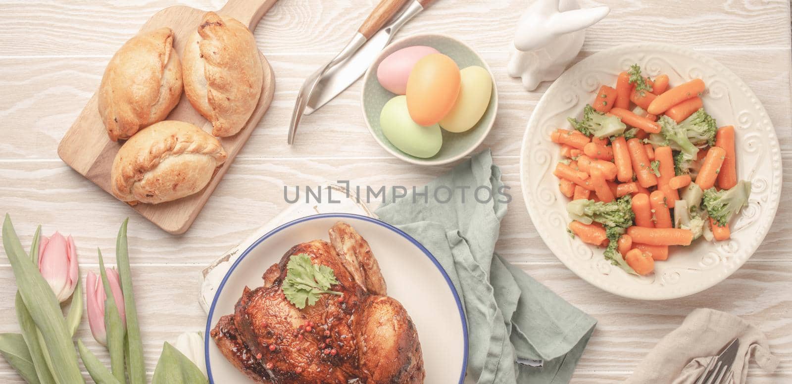 Easter food on white rustic table: colored eggs, roasted chicken, vegetables, buns by its_al_dente
