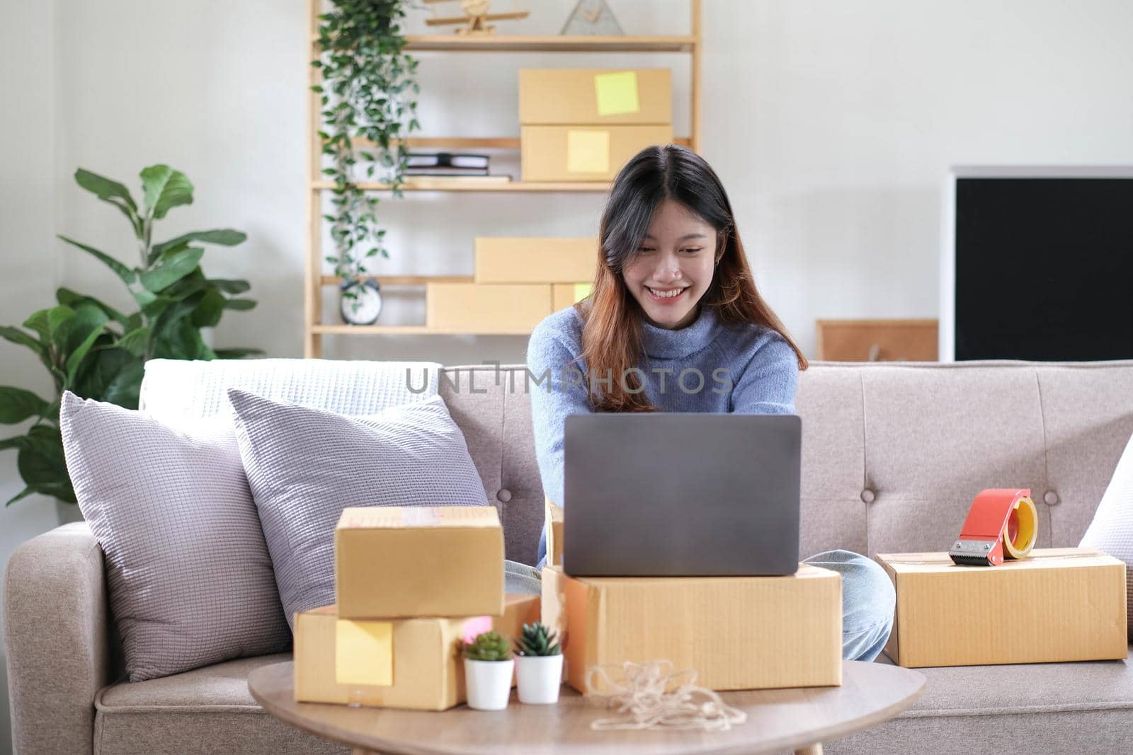 Startup SME small business entrepreneur of freelance asian woman using a laptop with box Cheerful success online marketing packaging box and delivery SME