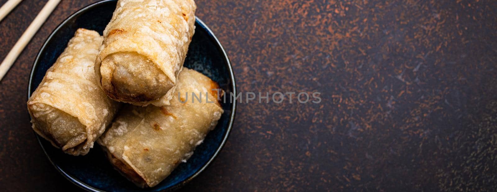 Chinese, Thai or Vietnamese traditional dish deep fried spring rolls with filling on plate with sweet sour sauce on rustic concrete background top view, Asian appetizer or snack with chopsticks copy space