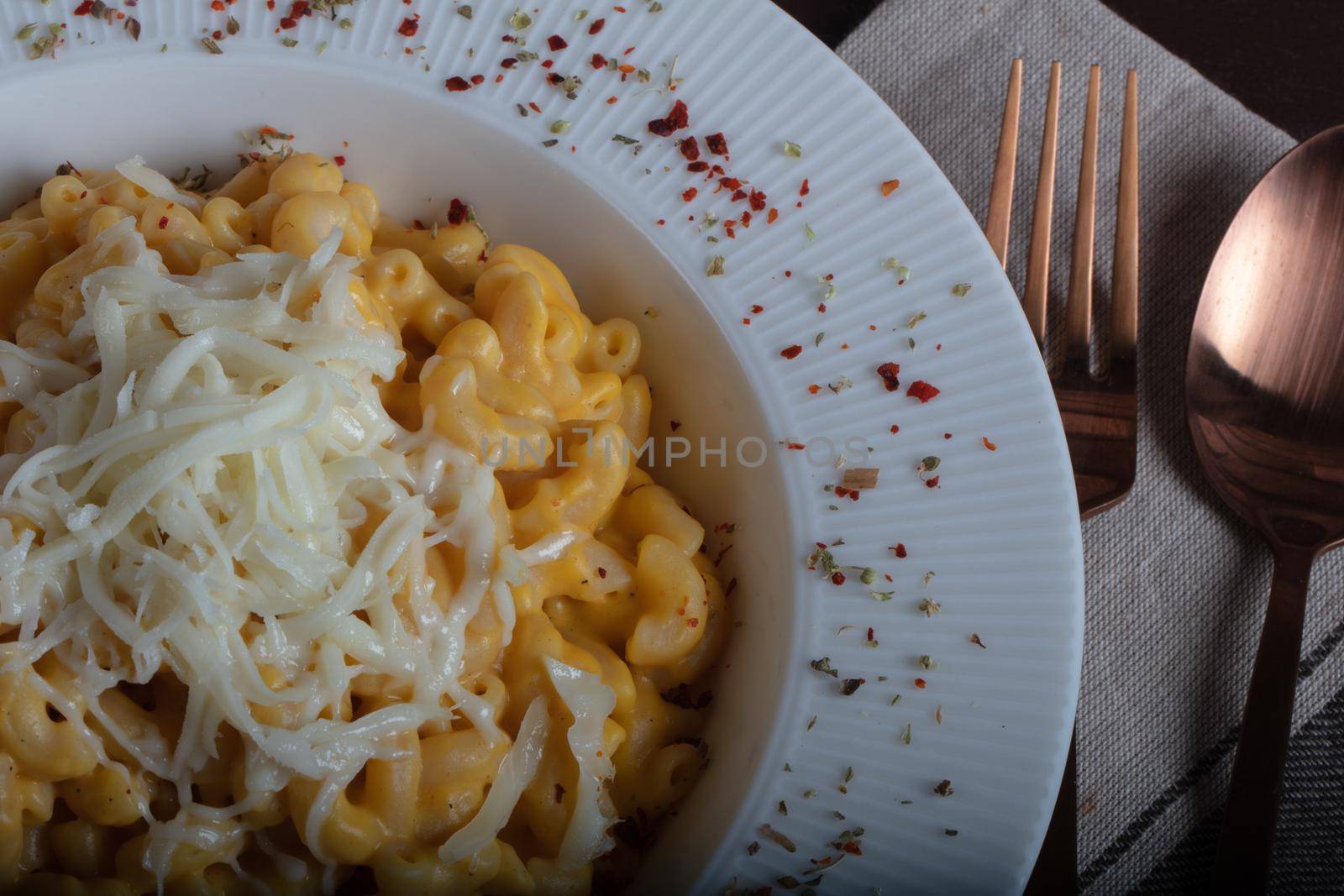 Mac and cheese, american style macaroni pasta with cheesy sauce on dark rustic table, top view by senkaya