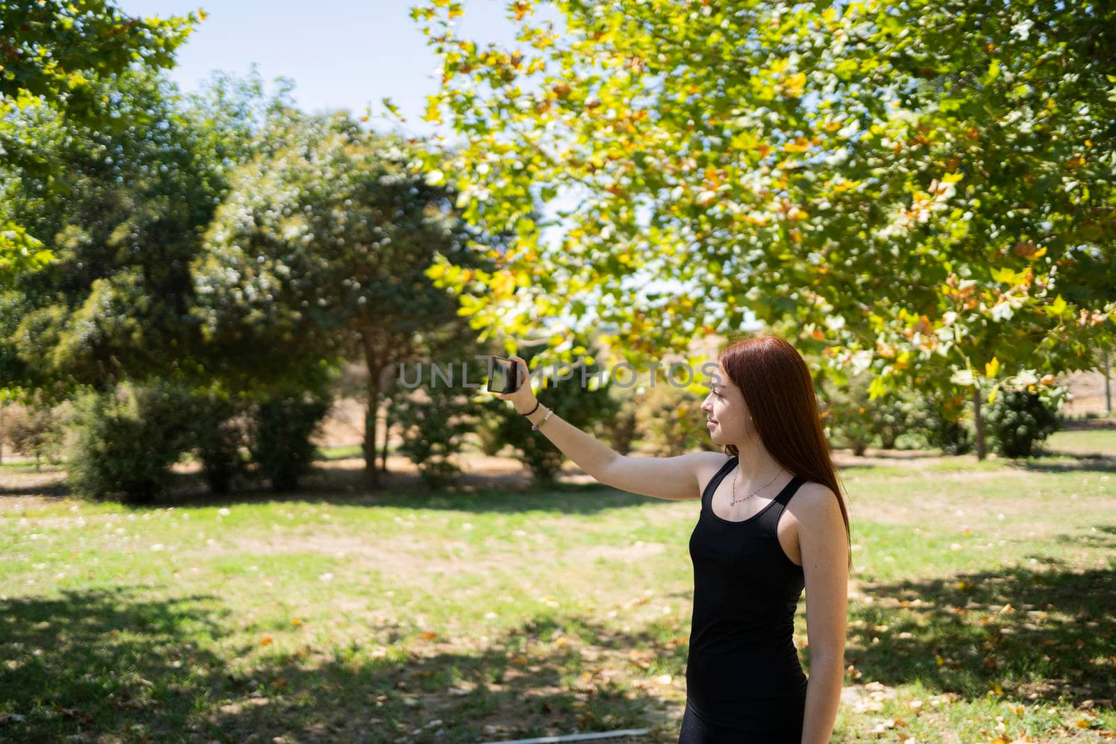 Young woman taking selfie in the park while exercising by barcielaphoto